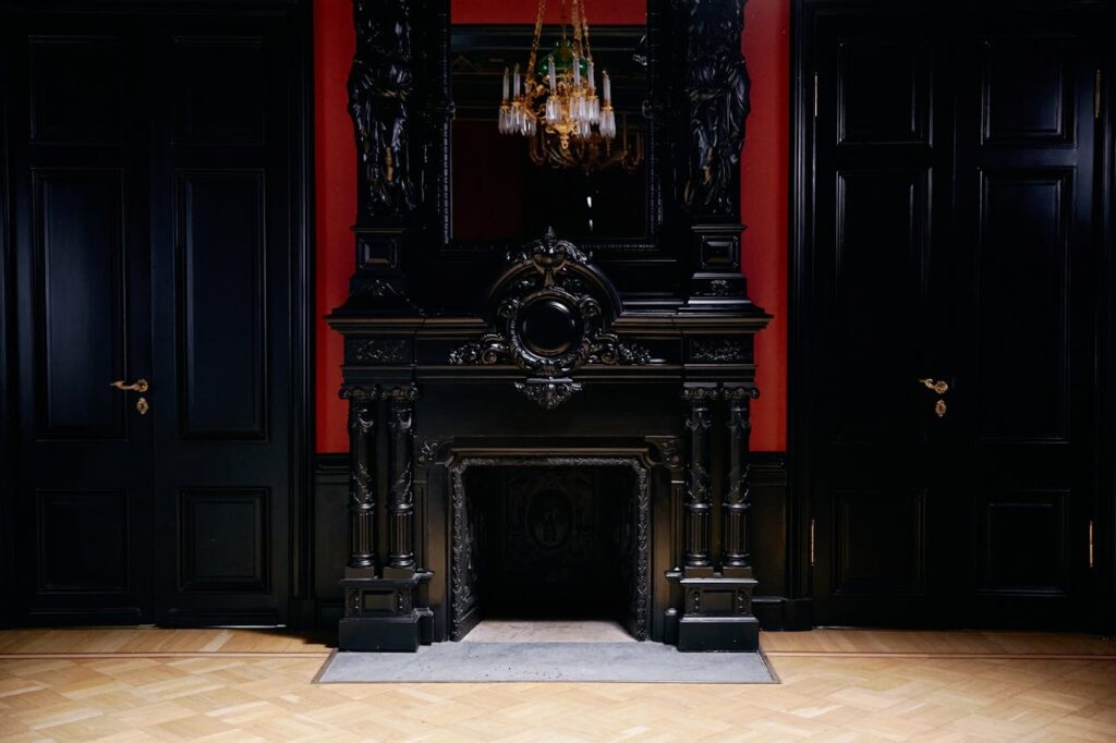 Luxurious vintage interior with ornate black fireplace and classic chandelier, perfect for elegant decor inspiration.